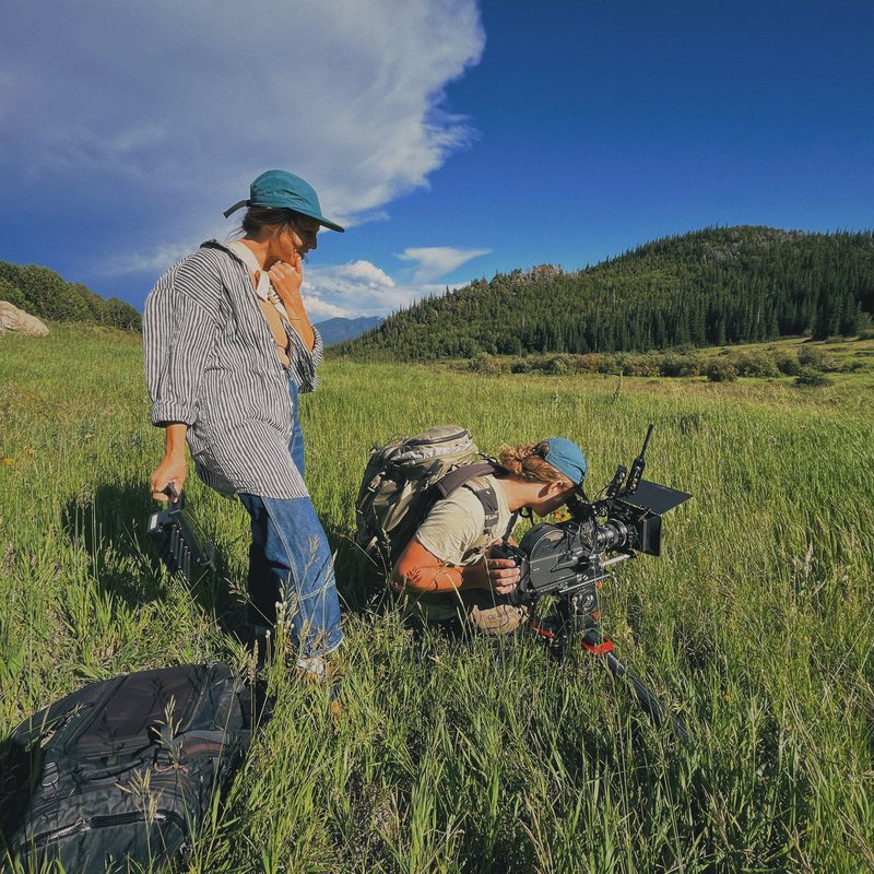 Camera operator filming low in a mountain meadow