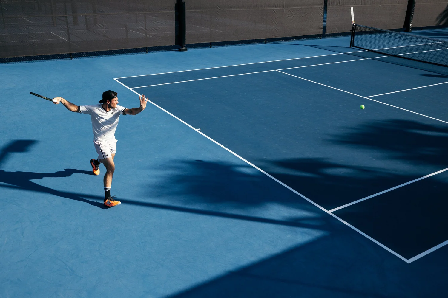Tommy Paul mid-forehand on a blue hard court