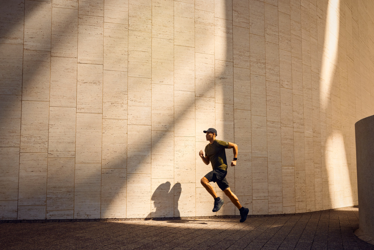 Runner in low afternoon light against a travertine wall